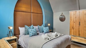 A bedroom with a large arched headboard, a wooden wardrobe, and a bedside lamp.