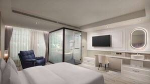 A modern hotel bedroom with a large bed, a seating area, a glass-enclosed shower, a vanity with a mirror, and a flat-screen TV. - Tryp By Wyndham New Taipei Linkou (New Taipei City)