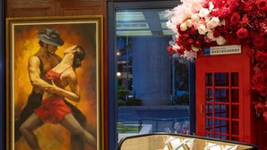A lobby with a checkered floor, a green sofa with patterned cushions, a red telephone booth, and a large painting of dancers. - Tryp By Wyndham New Taipei Linkou (New Taipei City)