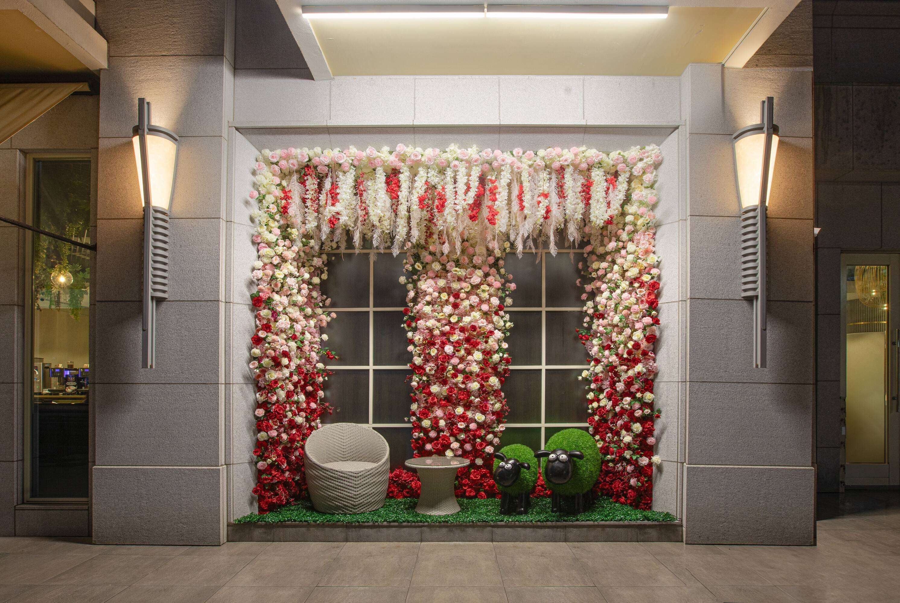 A decorated window display with floral arrangements and a seating area.