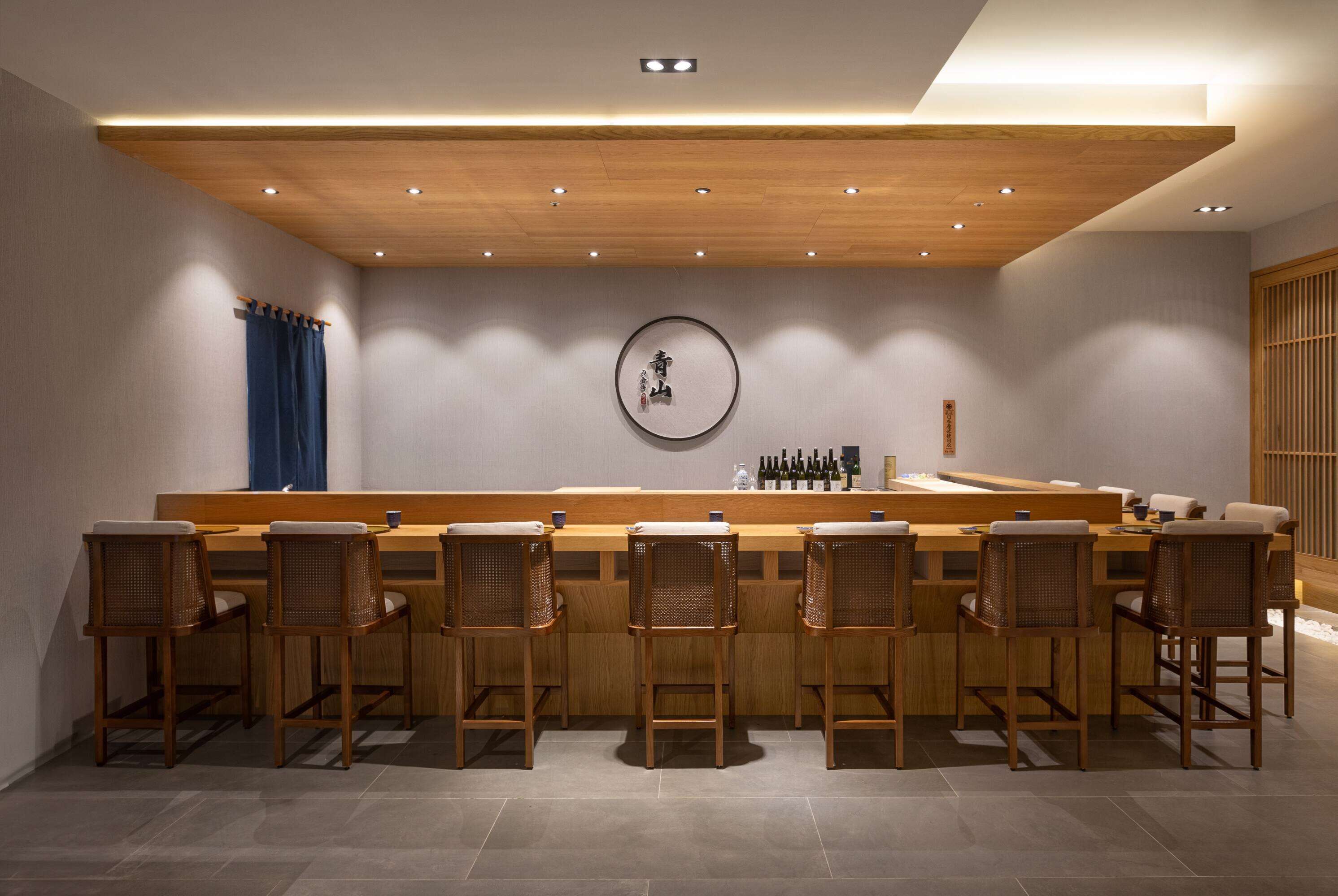 Un espace bar moderne, doté de mobilier en bois et d’une table ronde centrale.