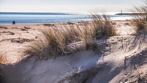 Una playa con dunas de arena y una vista distante del mar.