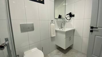A modern bathroom with a toilet, sink, and shower.
