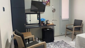 A compact living space with a kitchenette, a television, a small refrigerator, a trash bin, and two chairs. - Eraliz (Izmir)