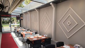 A restaurant with outdoor seating, tables set with white plates and silverware, and a red carpet leading to the entrance. - Eraliz (Izmir)