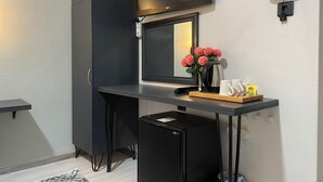 A compact kitchenette with a black refrigerator, a small countertop, a kettle, and a tray with cups and a bag of snacks. - Eraliz (Izmir)