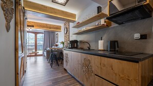 A modern kitchen with wooden cabinetry, a black countertop, and built-in shelves. - Korona Giewontu 3 (Koscielisko)