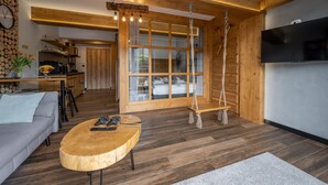 A modern living room with a wooden ceiling, a large window, a swing, a TV, and a sofa. - Korona Giewontu 3 (Koscielisko)