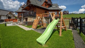 A wooden cabin with a slide and climbing structure in a grassy yard. - Korona Giewontu 3 (Koscielisko)