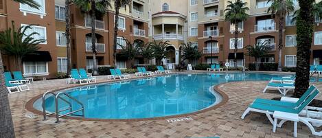 A pool area with lounge chairs and palm trees.