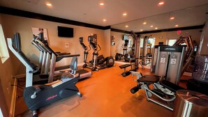Een sportschool met diverse trainingsapparaten, waaronder loopbanden, crosstrainers en krachttoestellen.
