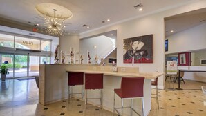 Een moderne lobby met een receptiebalie, een bar en een trap.