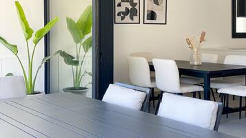 Un comedor moderno con una mesa de madera oscura, sillas blancas y plantas en macetas.