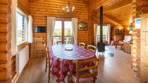 A log cabin with a dining area featuring a table with chairs, a chandelier, and a fireplace. - Chalet les deux marmottes - Vue montagne (Bolquère)