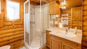 A wooden cabin bathroom with a glass-enclosed shower, a sink, and wooden cabinets. - Chalet les deux marmottes - Vue montagne (Bolquère)
