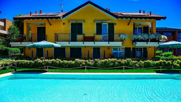A yellow building with balconies and a swimming pool in front. - Infinity Apartment by Wonderful Italy (Bellagio)