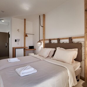 A hotel room with a large bed, a bedside table, a lamp, and a wall-mounted phone. - D And D Resort (Hersonissos)