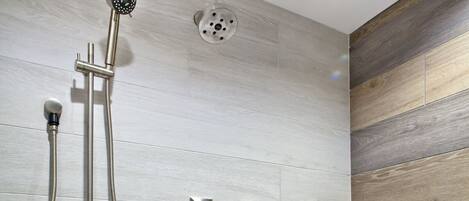 A modern bathroom with a shower, control panel, and a unique wood-patterned wall design.