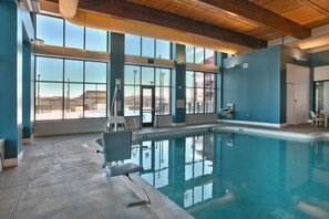 An indoor swimming pool with clear views of the outside, large windows, and a poolside seating area. - Walker's Bluff Casino Resort (Carterville)