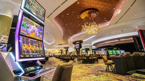 Een casino interieur met gokautomaten, een grote kroonluchter en een vloerbedekt met tapijt.