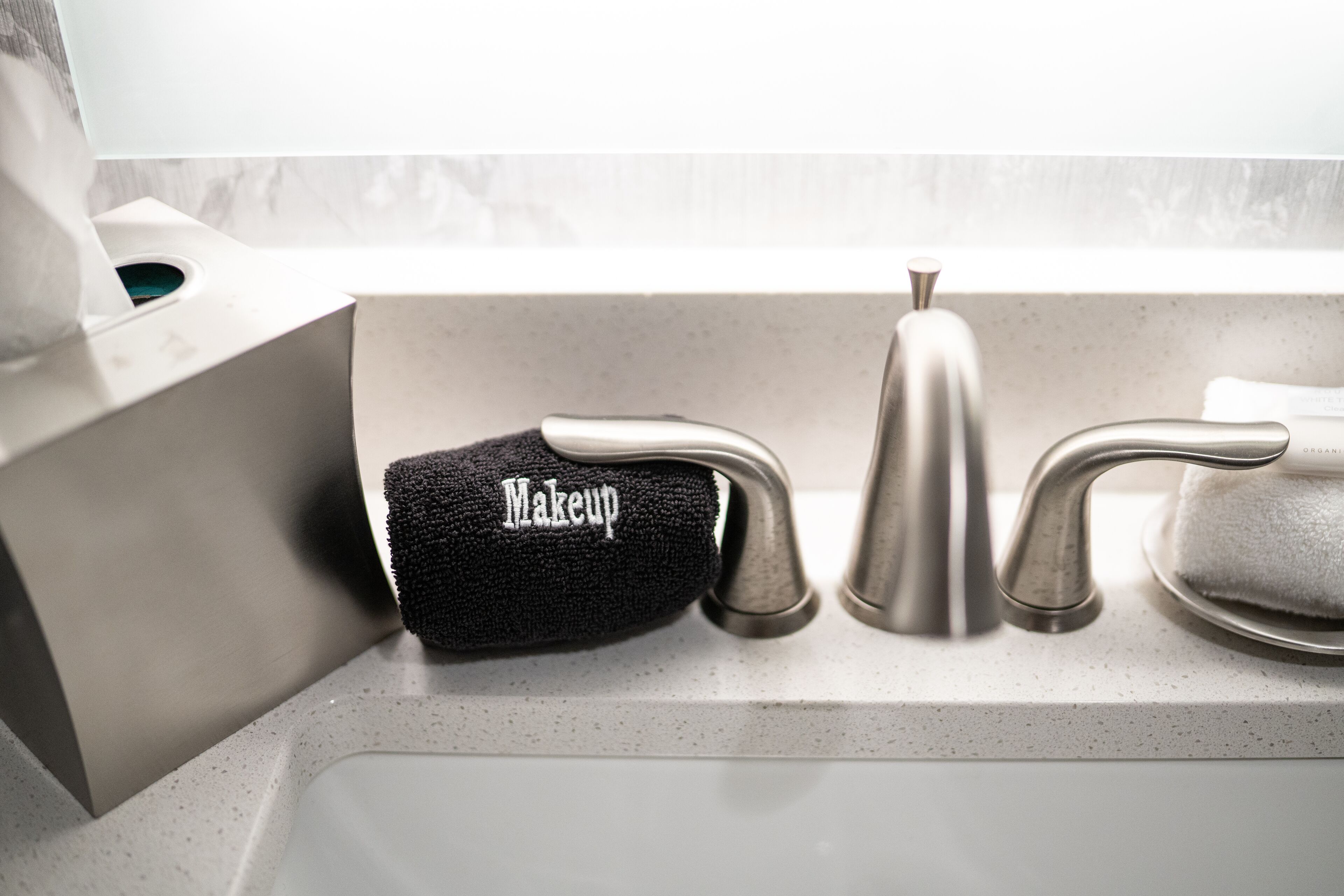 A bathroom sink with a makeup towel and a soap dispenser.