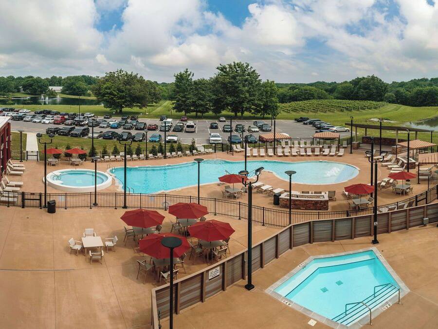 Un espace piscine sur le toit, comprenant plusieurs piscines, des chaises longues et des parasols.