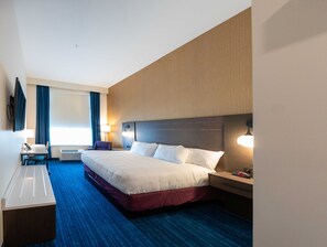 A hotel room with a large bed, a desk with a chair, a TV, and a window with curtains. - Walker's Bluff Casino Resort (Carterville)