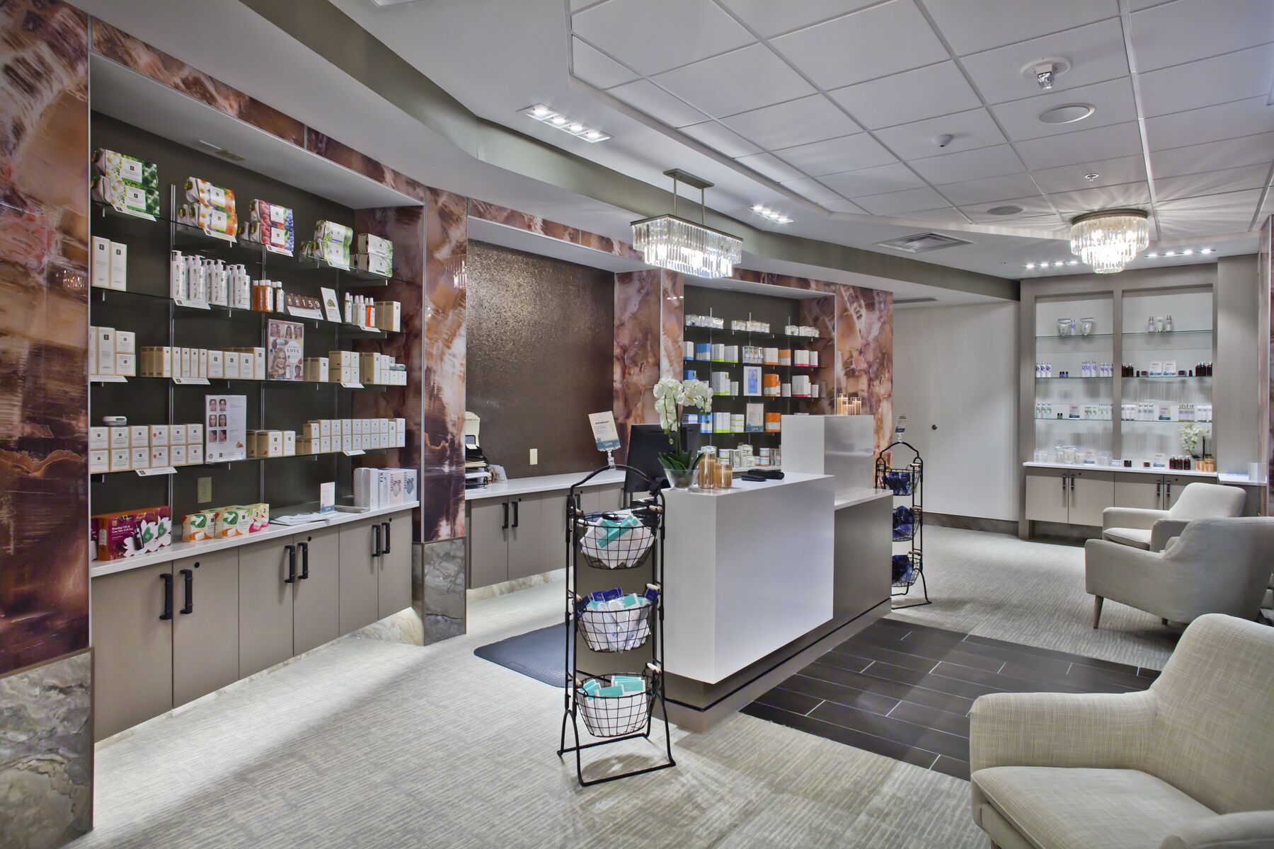 A modern reception area with a marble wall, shelves of products, a reception desk, and seating.