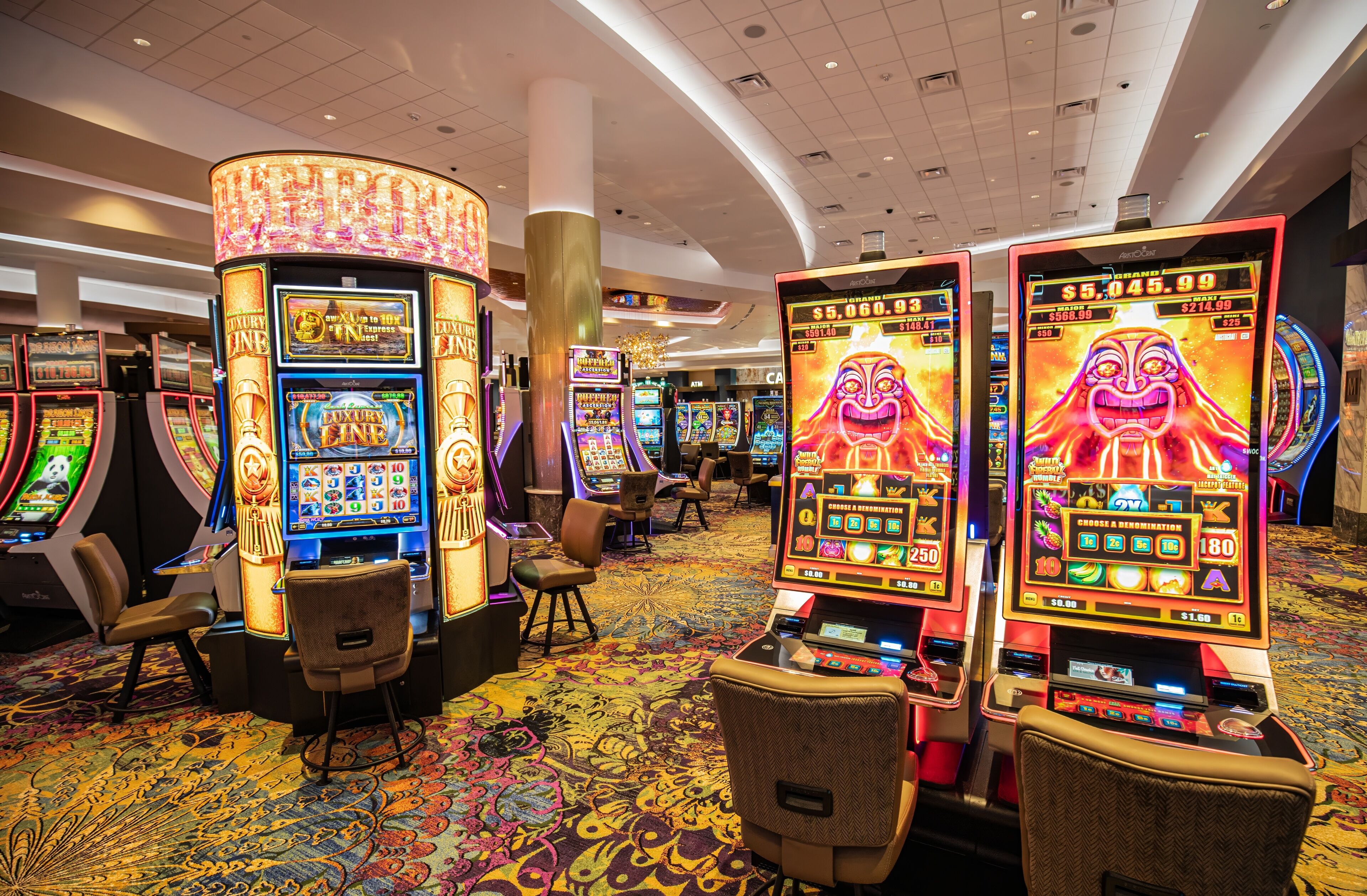 Un casino amb diverses màquines escurabutxaques, seients i una catifes amb dibuixos.