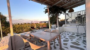 An outdoor patio with a table and chairs, a hanging swing, and a view of the landscape.
