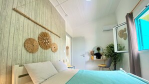 A bedroom with a bed, a bedside table, a chair, a mirror, and a window with curtains.