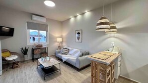 A modern living room with a sofa, coffee table, and a dining area with a table and chairs.