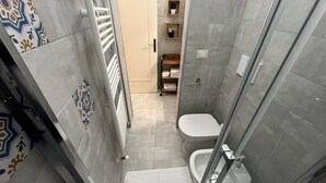 A small bathroom with a shower, toilet, and a tiled floor. - Studio apartment on padreterno street in nardò to relax, 5 minutes from the beach  (Nardò)