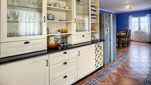 Una cocina con un mueble grande, un refrigerador y una zona de comedor con sillas y una mesa.