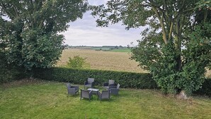 A grassy outdoor area with wicker furniture and a view of a field. - Charming Studio Rutland Point Holiday or Work (Oakham)