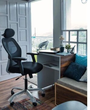 Relax in this stylish room with a large window offering a view of the outdoors, a comfortable sofa, and a desk for work or relaxation.