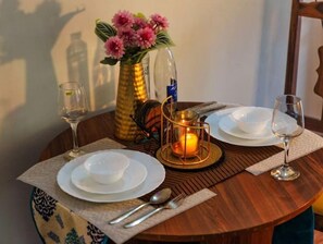 A beautifully set table for two, featuring fine china, a glass wine glass, and a vase with fresh flowers.