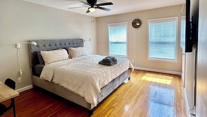 Une chambre à coucher avec un lit, un ventilateur de plafond et un plancher en bois.