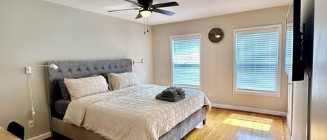 A bedroom with a bed, ceiling fan, and wooden flooring.