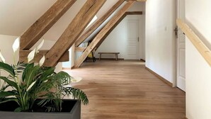 An attic room with exposed wooden beams, a wooden floor, a bench, and a potted plant. - Cottage au coeur du Perche (Souancé-au-Perche)