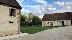 A building with a brick facade and a large open courtyard. - Cottage au coeur du Perche (Souancé-au-Perche)