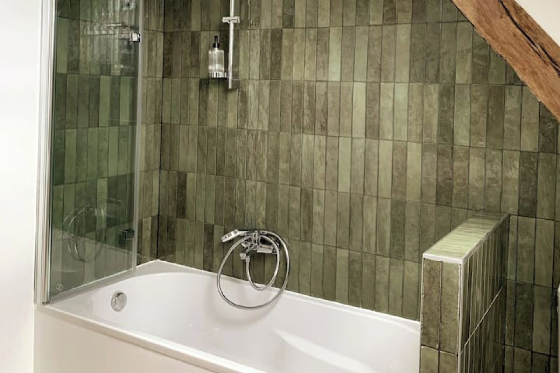 Une salle de bain moderne avec une douche à l’italienne en verre, une baignoire blanche et un mur carrelé.