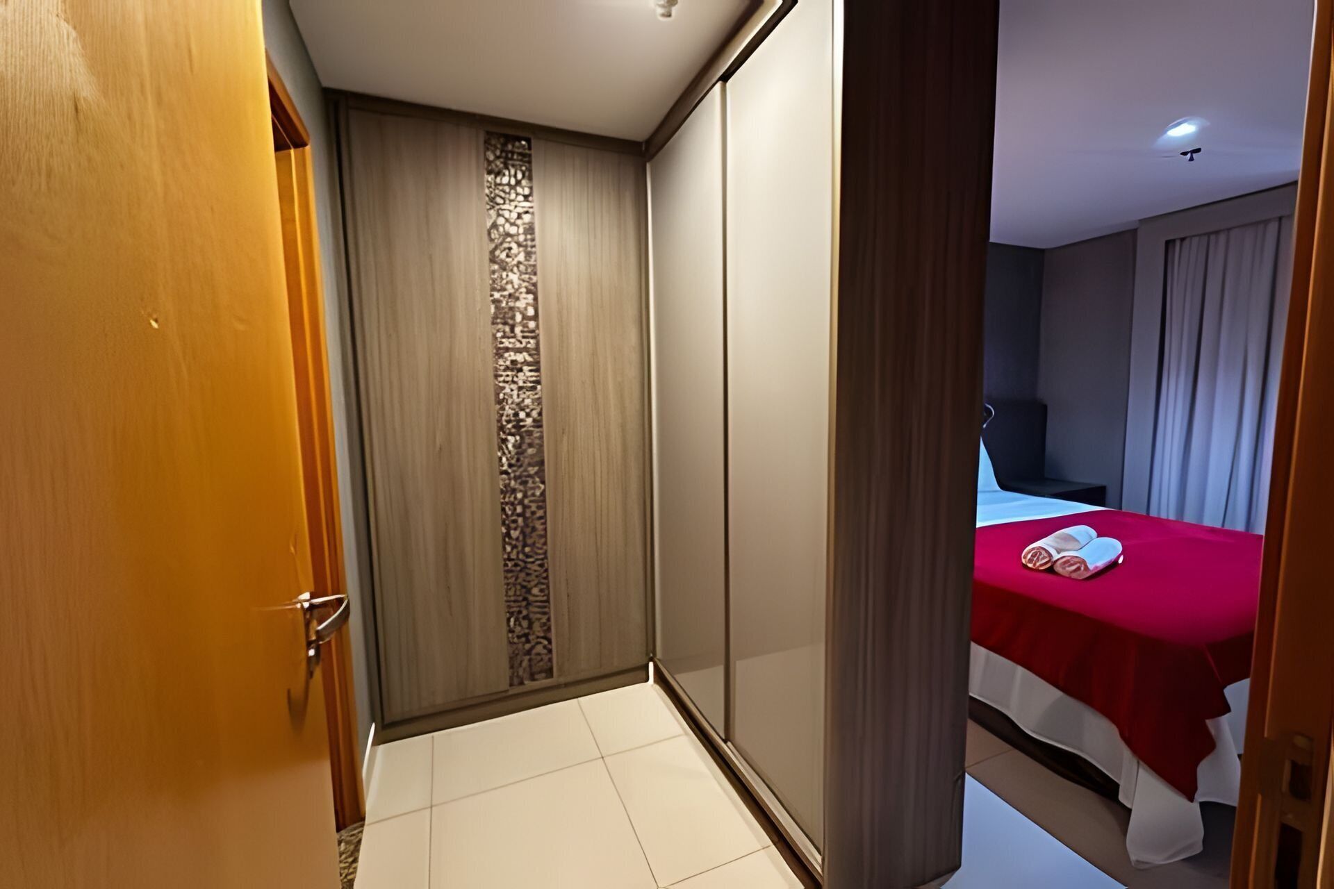 Ein Hotelzimmer mit einem Bett, einer Holztür und Blick auf ein weiteres Zimmer.
