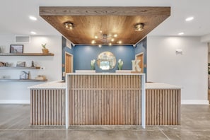 A reception area with a wooden ceiling, a round mirror, and a reception desk. - The Kingston Hotel (Garden City)