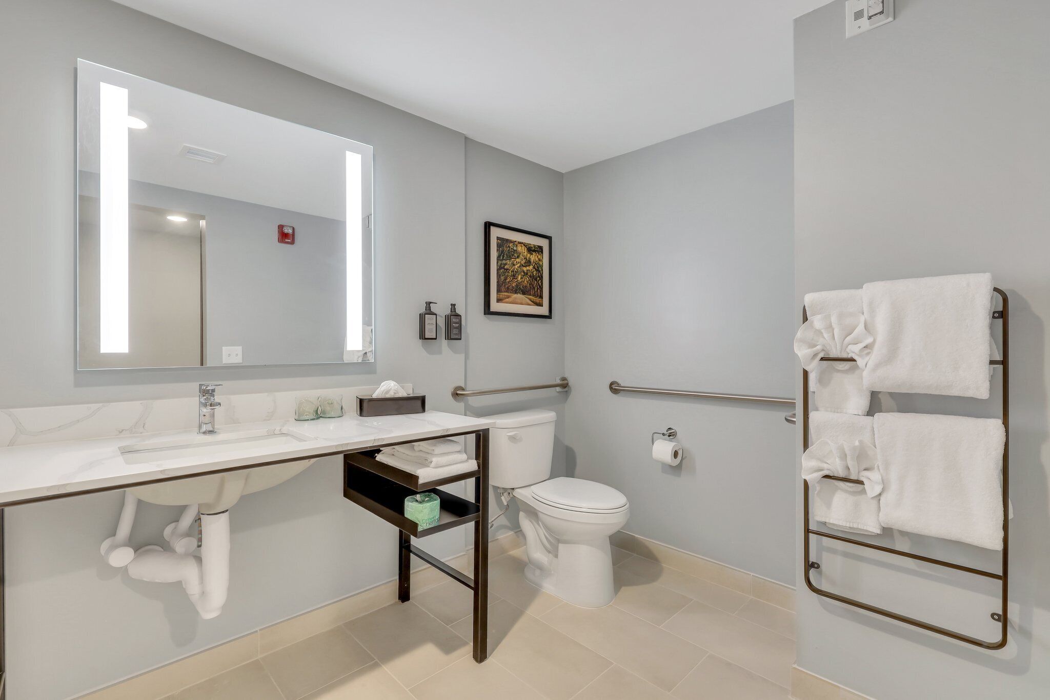 A modern bathroom with a white sink, mirror, toilet, and towel rack.