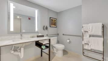 A modern bathroom with a white sink, mirror, toilet, and towel rack.