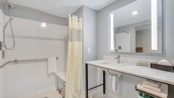 A modern bathroom with a shower, a toilet, a sink, and a mirror.