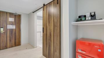 A hallway with wooden doors, a red storage unit, and a shelf with mugs.