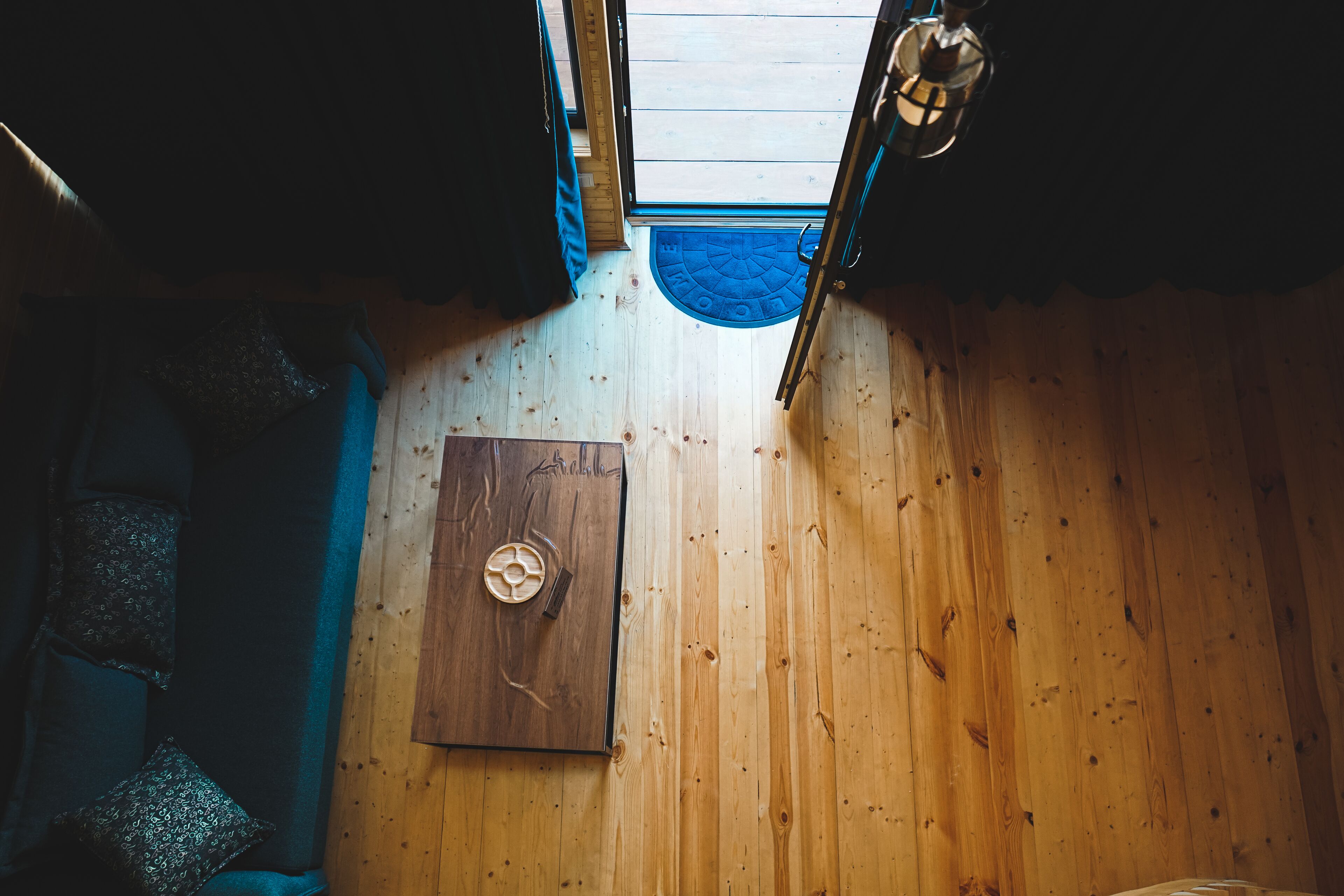 Een houten interieur met een deur, een blauwe mat en een plafondlamp.