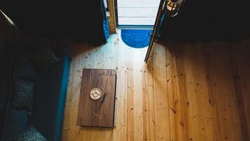 Een houten interieur met een deur, een blauwe mat en een plafondlamp.